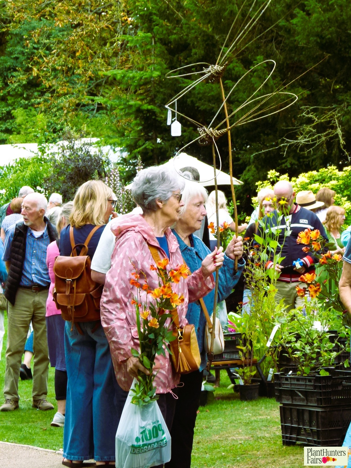 two ladies holding bags of plants and woven willow dragonflies